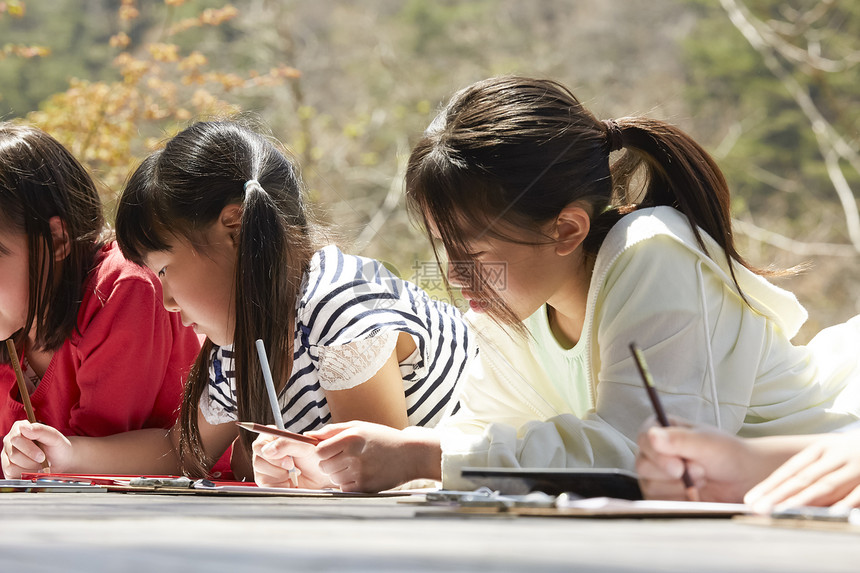 小学生趴在公园的地上写生图片