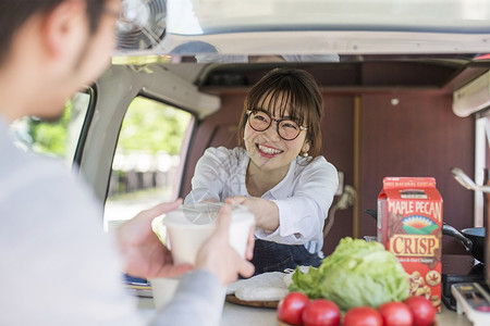 餐车里微笑的递出食物的年轻女性高清图片