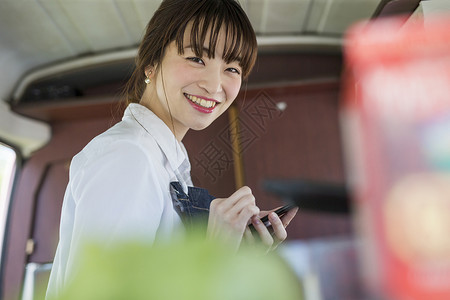 特卖专场餐车里拿着手机微笑的年轻女性背景