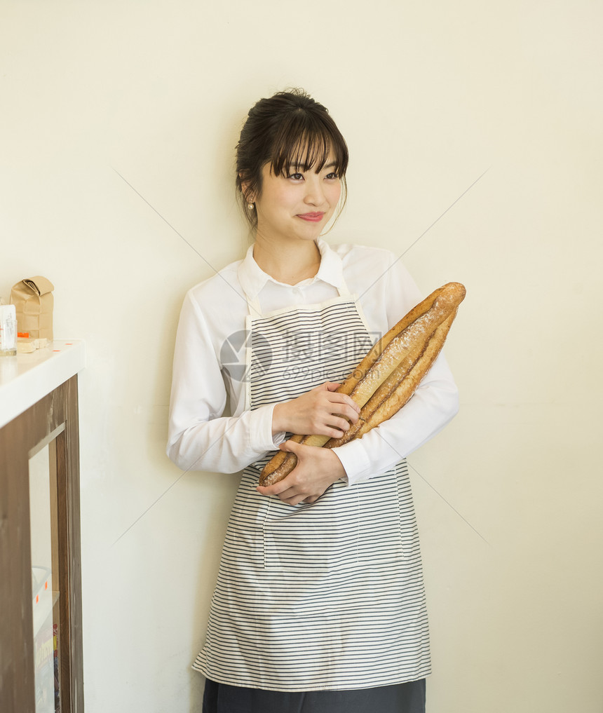 年轻女性抱着新鲜出炉的法式面包图片
