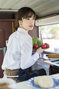 餐车里拿着新鲜蔬菜的年轻女性图片