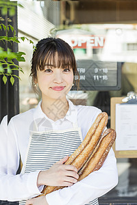 年轻女性微笑着抱着新鲜出炉的法式面包图片