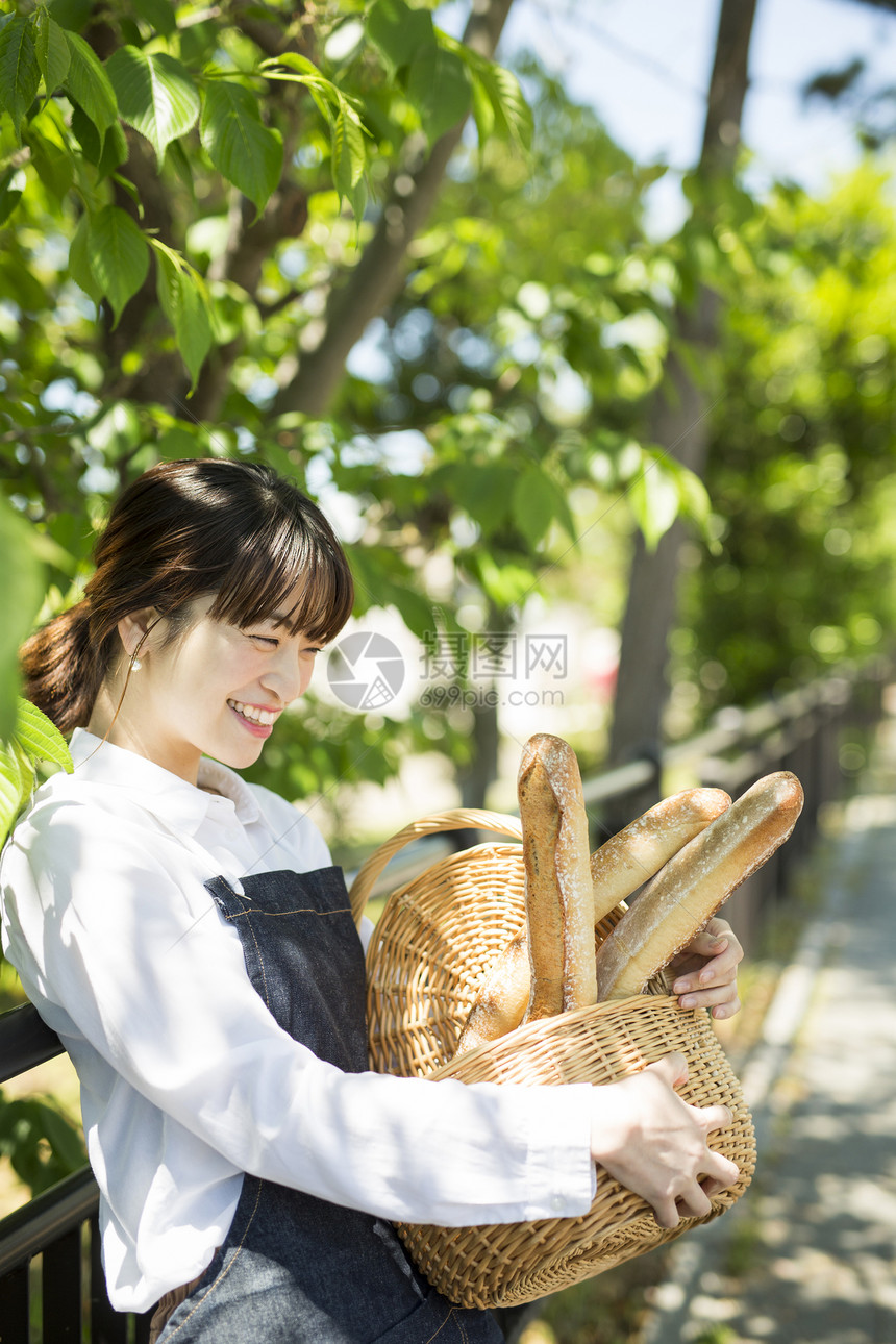 抱着一筐新鲜面包微笑的年轻女性图片