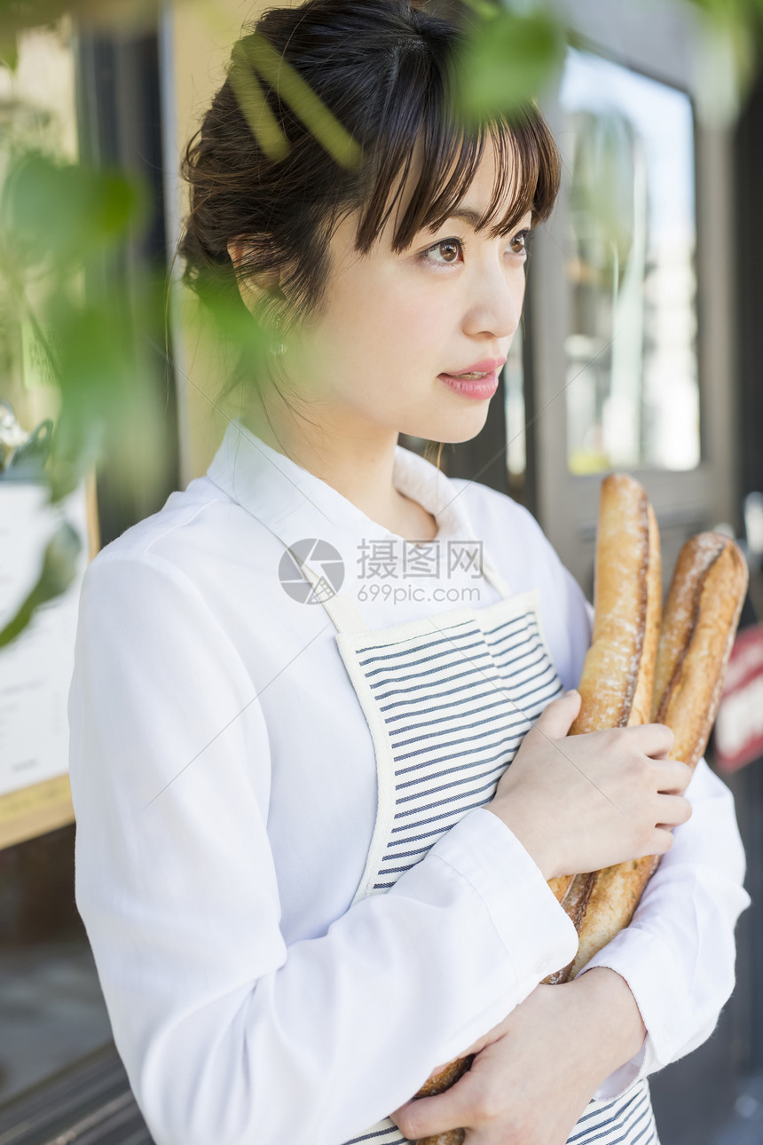 抱着法式面包的年轻女性图片