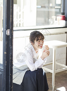 穿着围裙坐在咖啡馆里的店员图片