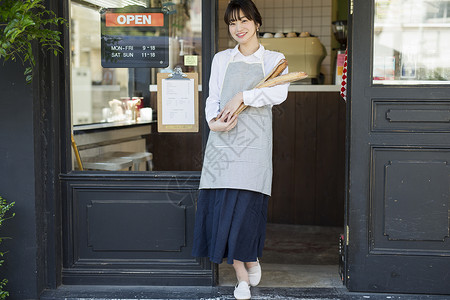 在咖啡店门口手拿面包的女人图片