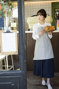 咖啡店女职员拿着新鲜出炉的面包图片