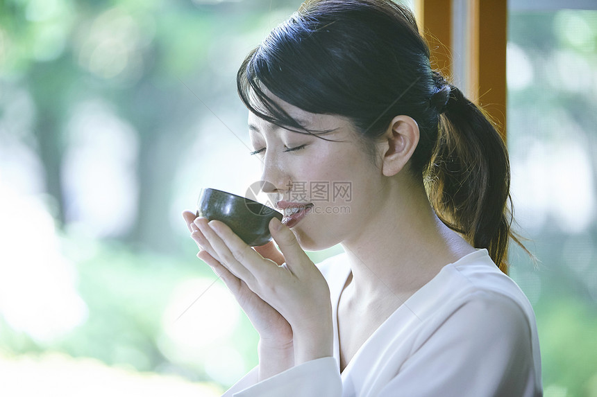 女人举起茶杯喝茶图片