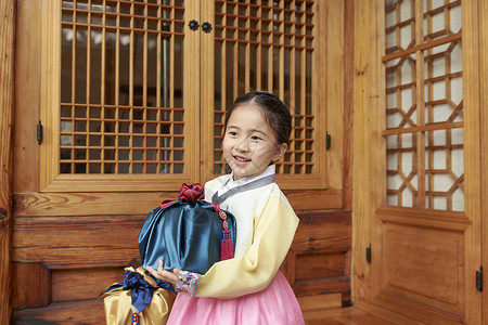 穿着韩国传统服饰的小女孩捧着礼物盒背景图片