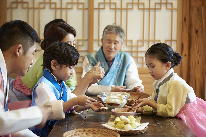 穿着韩国传统服饰的大家庭制作节日美食图片