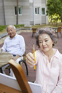 户外拿着画笔的老年女性高清图片