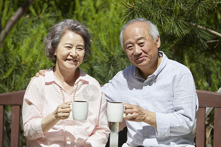 坐在长凳上喝茶的老年夫妇图片