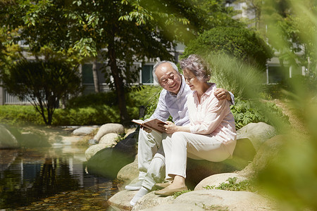 坐在岩石上看书的老年夫妇图片