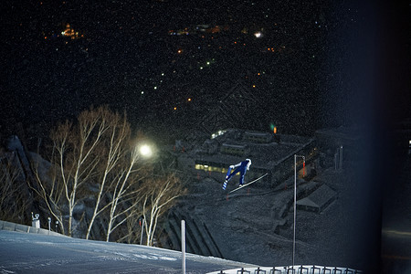夜晚滑雪场跳跃滑翔的运动员图片