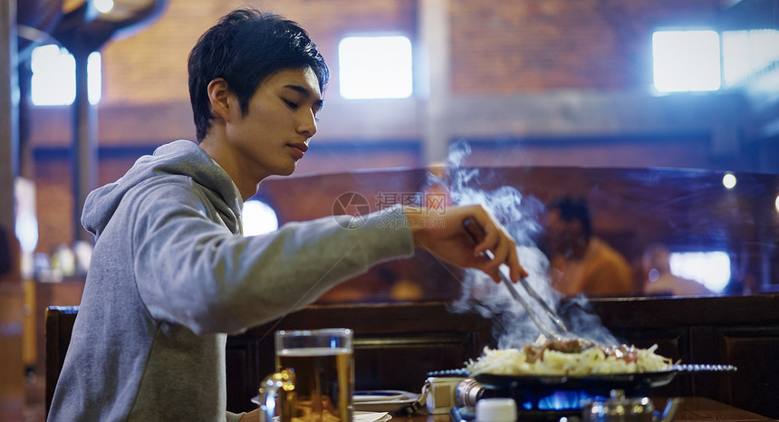 餐馆里独自烤肉的男青年图片