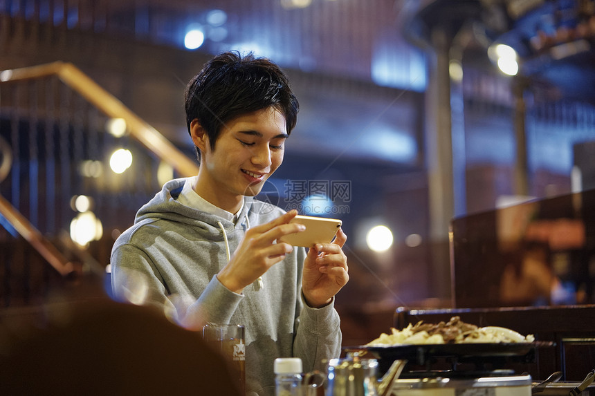 拿着手机拍照的男青年图片