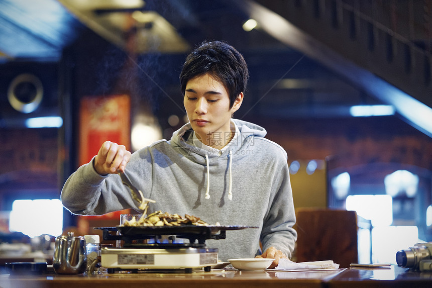 餐厅里独自烤肉的青年男性图片