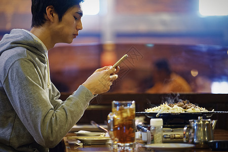 餐厅里拿着手机的男青年图片