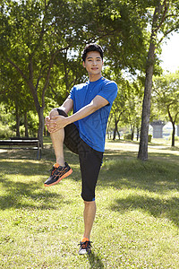 公园草坪伸展运动的男青年图片