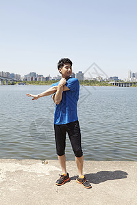 河岸边运动拉伸的男青年图片