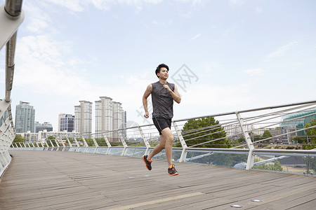 大桥上跑步运动的男青年高清图片