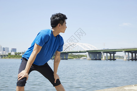 河岸边拉伸运动的男青年图片