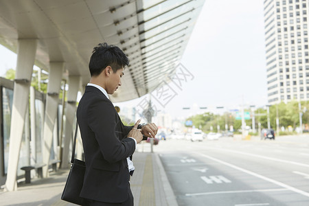 站在路边等车看手表的商务男性图片