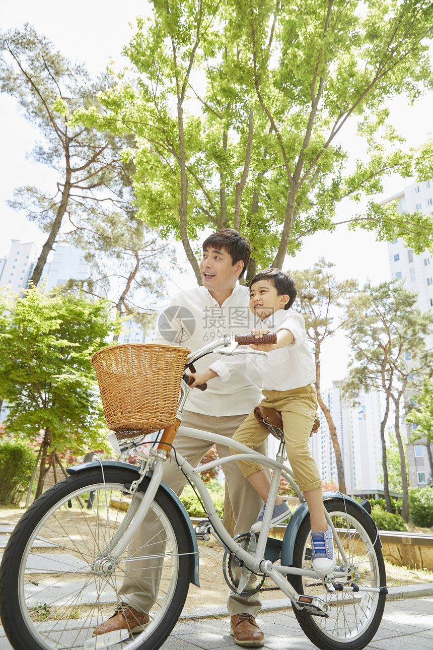 年轻爸爸陪着儿子骑自行车图片