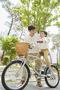 年轻爸爸陪着儿子骑自行车图片