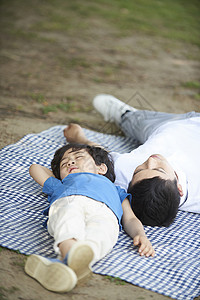 父亲和儿子在野餐垫上睡觉图片