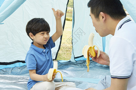 坐在帐篷中吃香蕉的父子图片