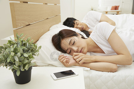 手机在妇女睡觉床头柜上图片