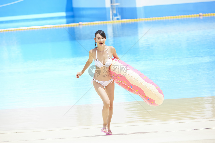 拿着游泳圈奔跑的年轻女性图片