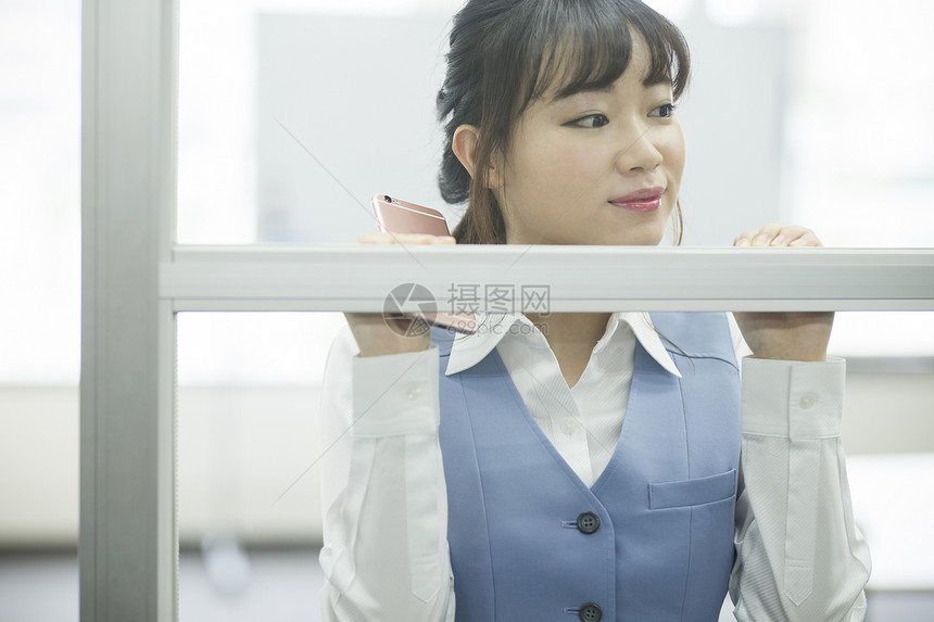 靠在办公室窗口的女性职员图片