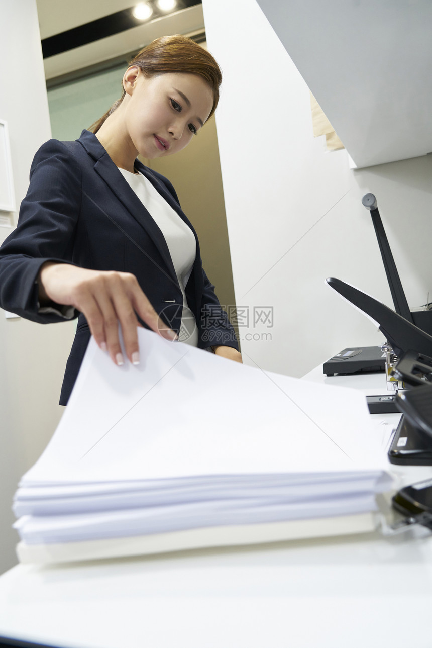 在办公室打印区拿文件的女白领图片