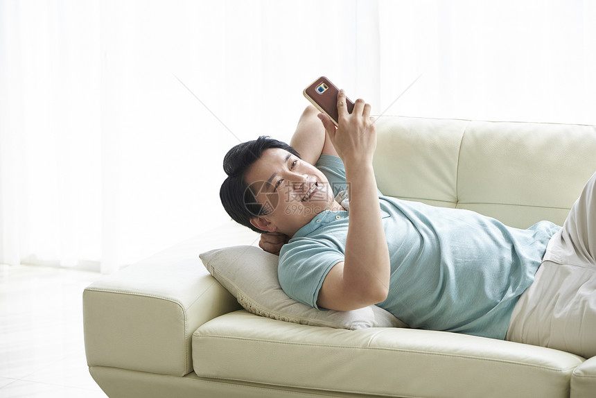 躺在沙发上看手机的中年男人图片