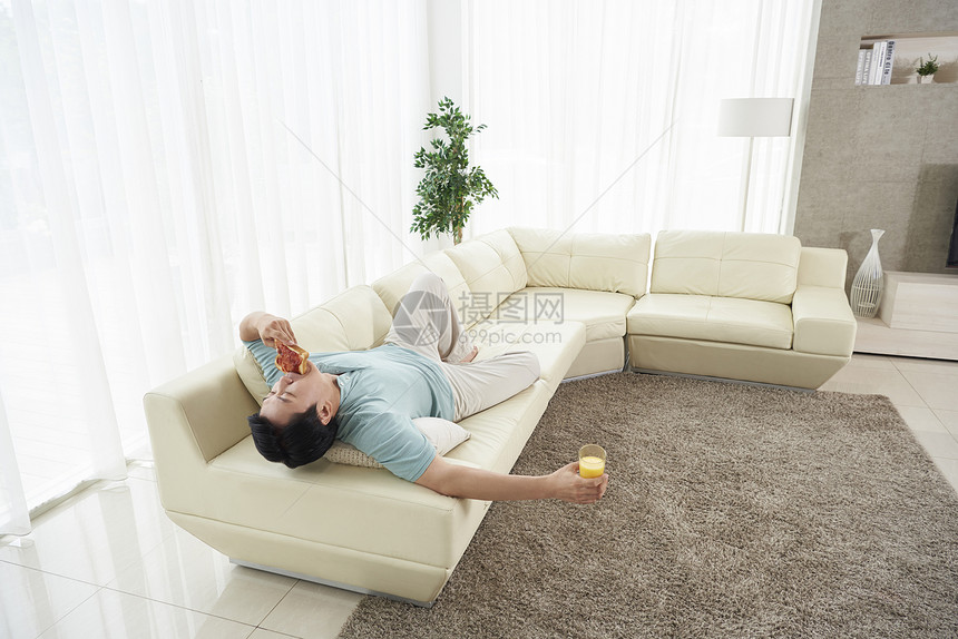 躺在沙发上吃面包的中年男人图片