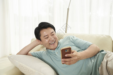 躺在沙发上玩手机的中年男人数字技术高清图片素材