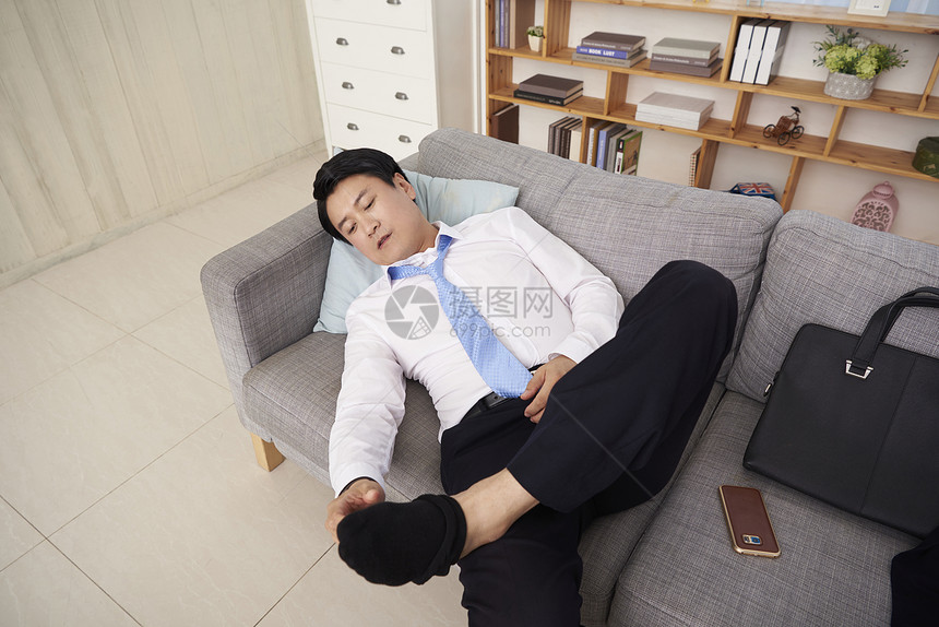 疲倦躺在沙发上休息的商务男人图片