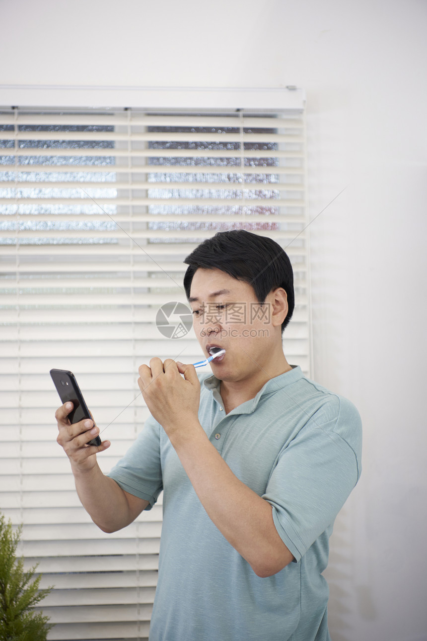 中年男子刷牙看手机图片