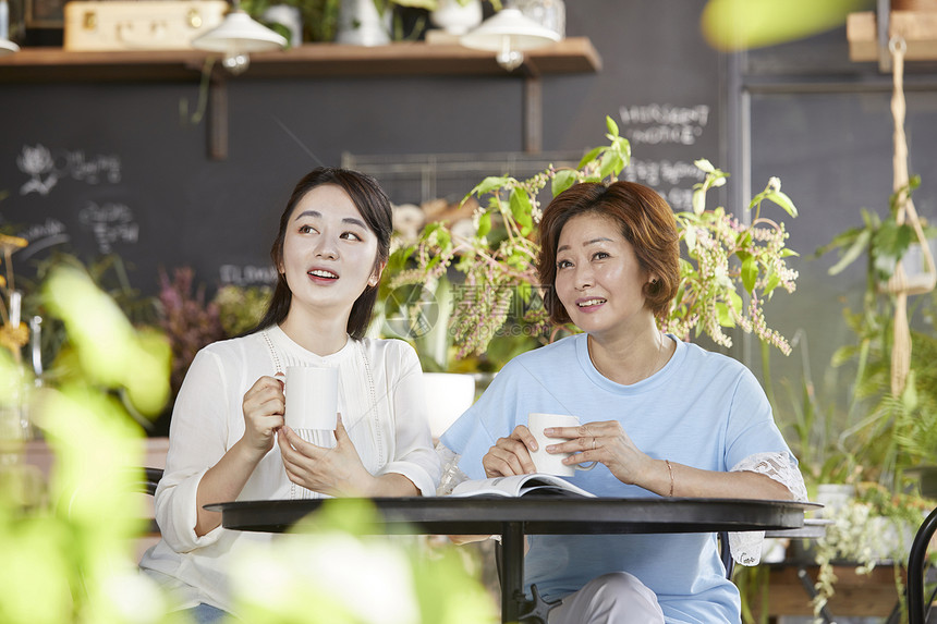 室内开心的母女坐一起喝咖啡看风景图片