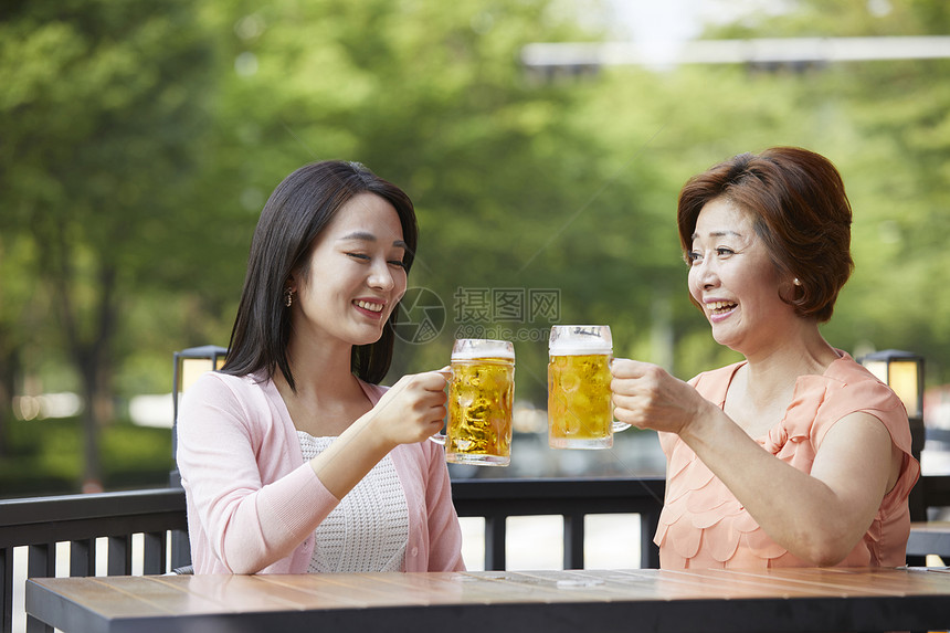 母亲和女儿一起户外喝啤酒图片
