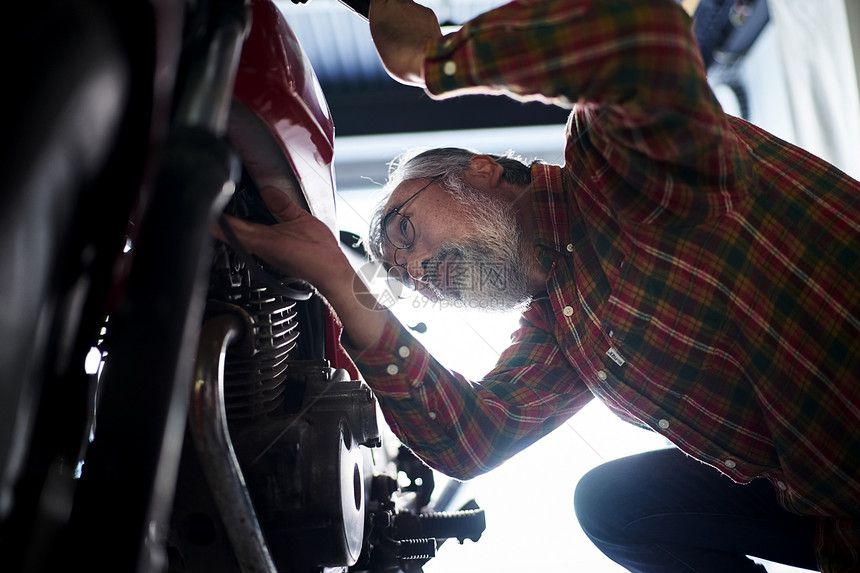 正在修理摩托车的老人图片