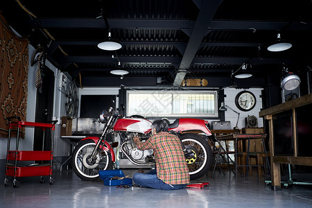 坐下修理摩托车的老人高清图片