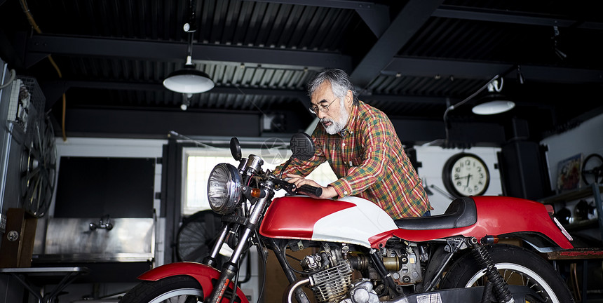 车库里修理摩托车的老人图片