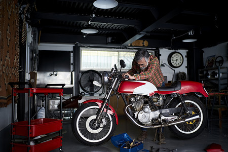 修理摩托车的老年男性图片