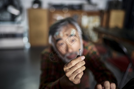 修理摩托车的老人特写图片