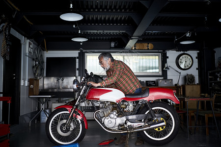 在室内修理摩托车的老人图片