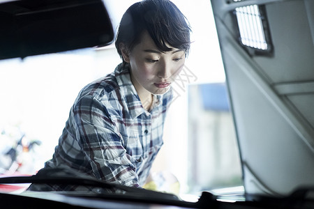 机房修理汽车的年轻女人图片