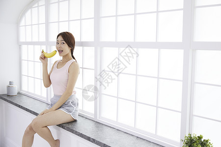 室内美丽的少女拿着香蕉图片